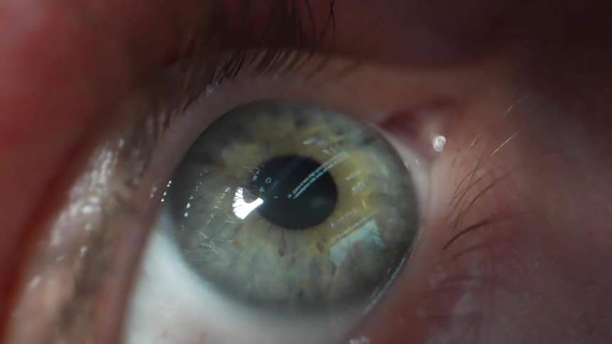 Extreme close up of a persons eye looking at a smartphone screen scrolling on social media