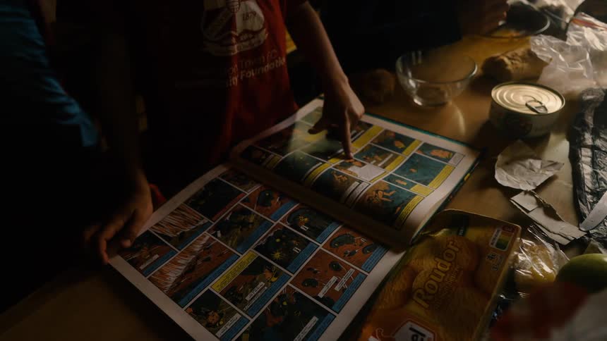 Hands of a child looking at a large illustrated book on the table