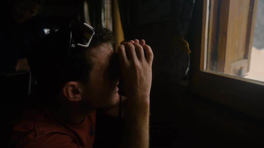 Man in an indoor space using binoculars