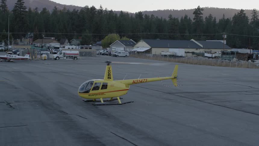 A helicopter is on the ground with its rotor spinning