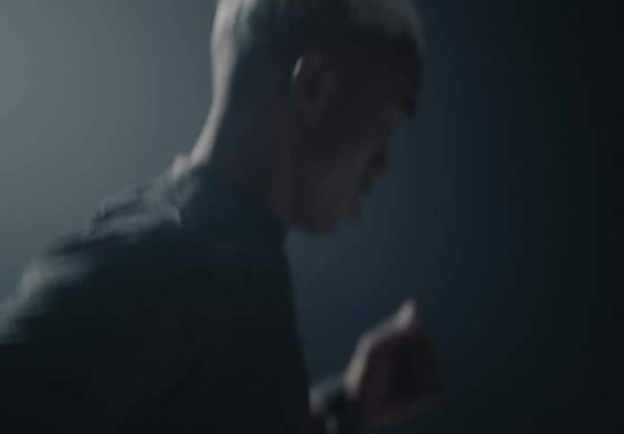 Man running in the dark while light flashes behind him