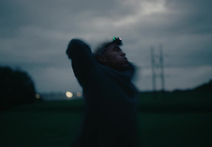 Man wearing a headlamp puts his hands on his heads while he walks to cool down after exercise