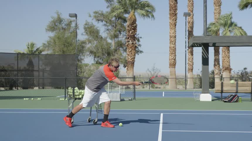 A man hits a tennis ball with a racket on a tennis court