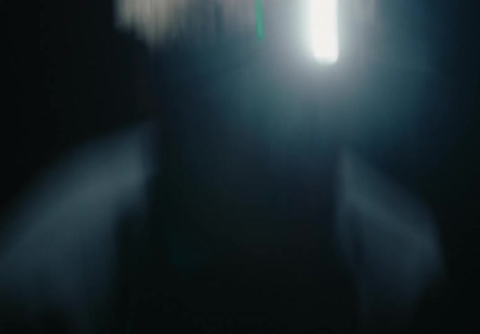 A person is walking halfstaggeringly while wearing a flashlight fixed on his forehead at night