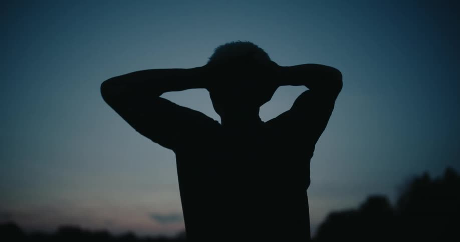 Silhouette of a man placing his hands behind his head