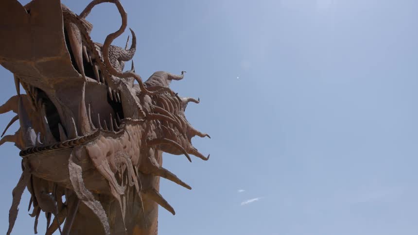 A massive dragon statue stands out against a blue sky on a sunny day