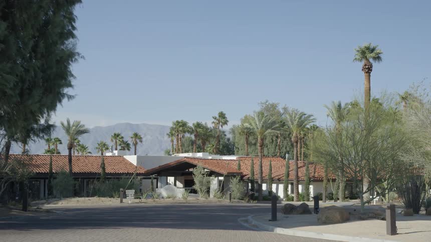Building surrounded by palm trees with mountains in the background on a clear day