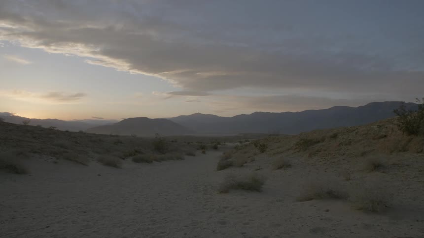 The sun is setting in a desert landscape