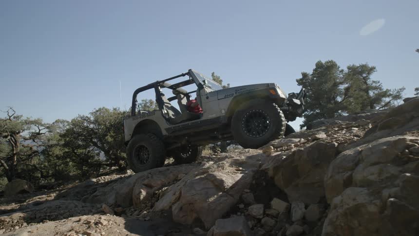 A jeep climbs a steep rocky hill