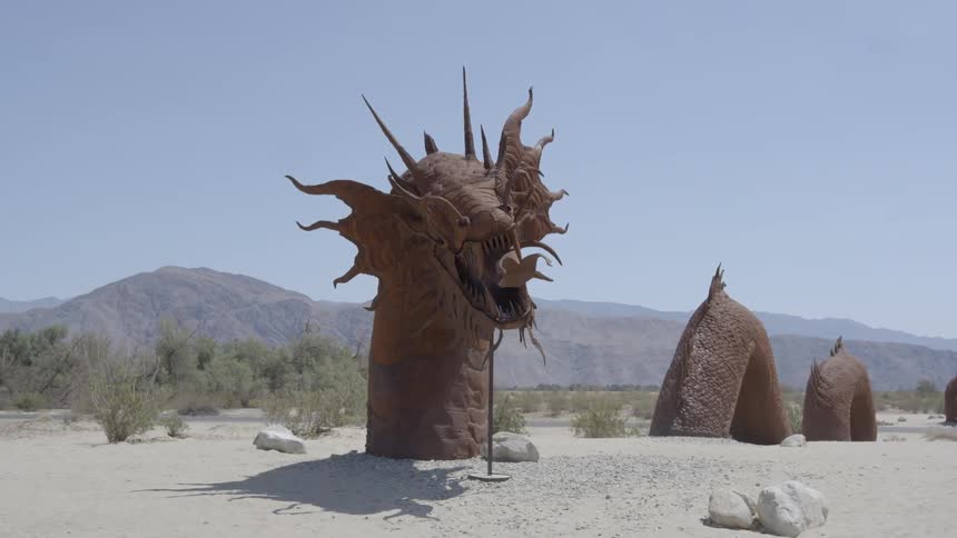 A dragon sculpture sits in the desert on a clear day