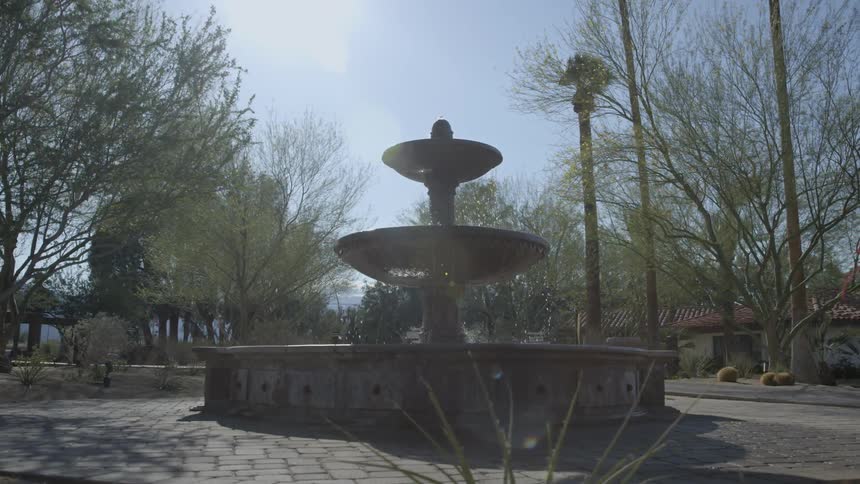 A tiered fountain is flowing in a plaza on a bright day