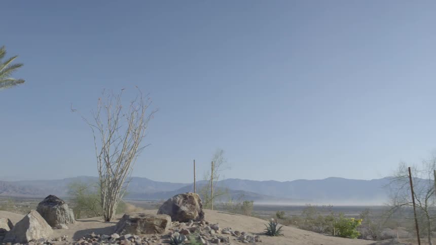 Moving view of some barren oasis with mountains in the background on a clear day