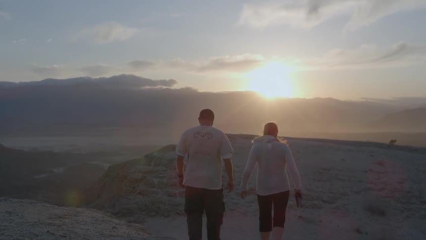 A man and woman hike in the mountains at sunset