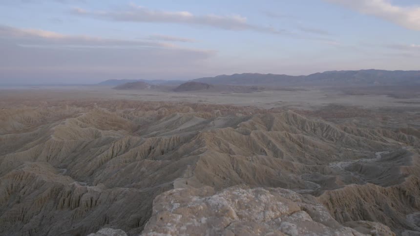 A tall cliff has another mountain range below