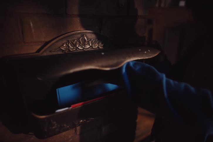 A young boy removes a letter from a decorative dark bronze mailbox mounted on a brick wall