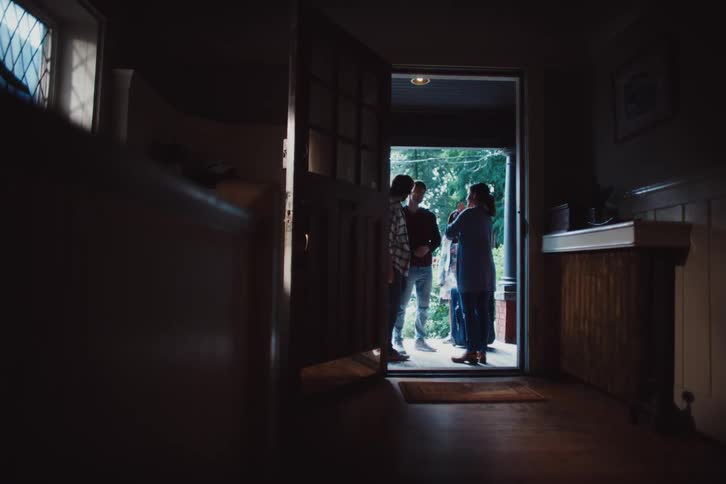 Friends next to the front door greeting each other and a dog walking down the hallway