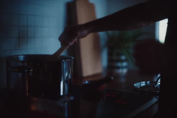 Hand holding a spatula and cooking