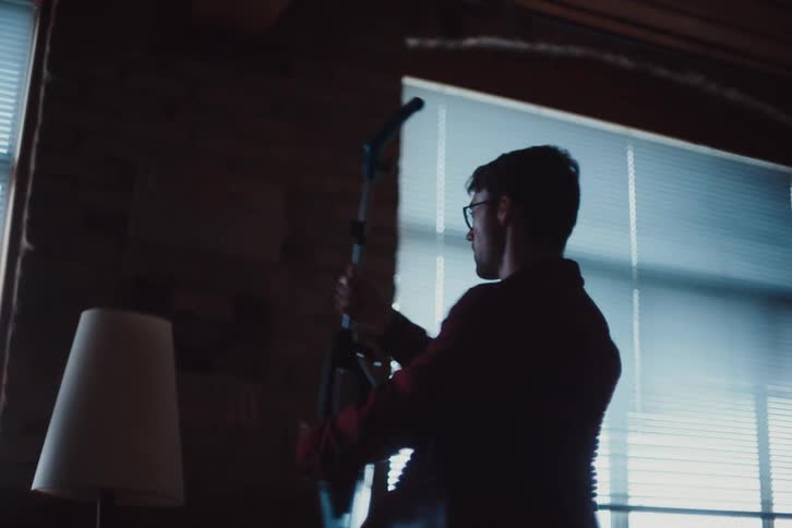 Man with glasses playing with vacuum cleaner