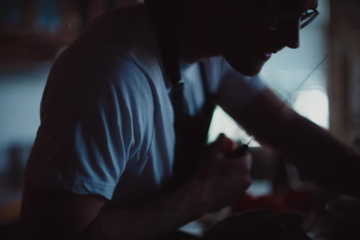Man consults a cookbook while preparing vegetables in the kitchen