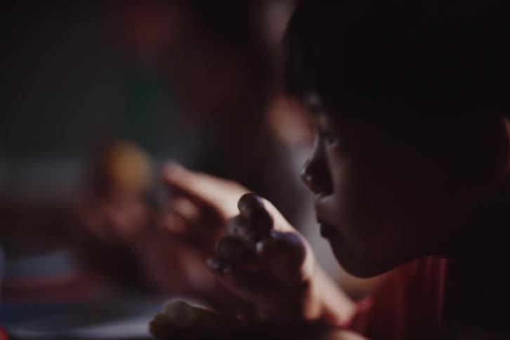 A child eating in a dimly lit setting creating a calm and intimate atmosphere