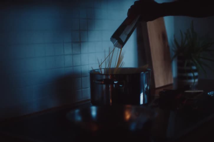 Man pouring pasta into a pot of boiling water on the stove
