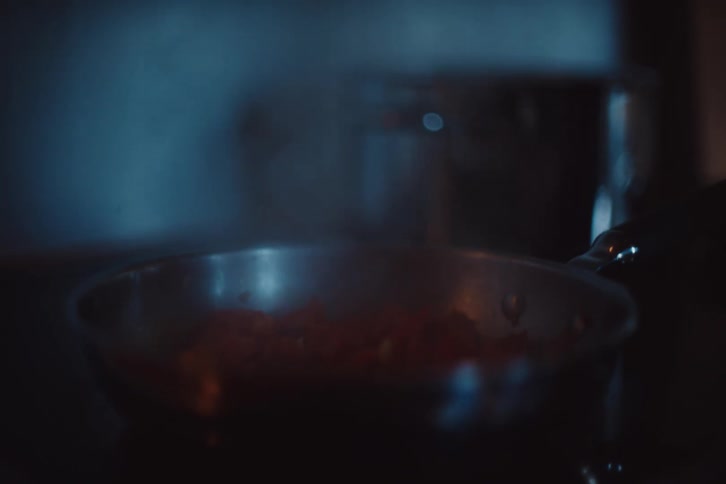 A steaming pot on a stove creates a warm atmospheric scene in dim lighting