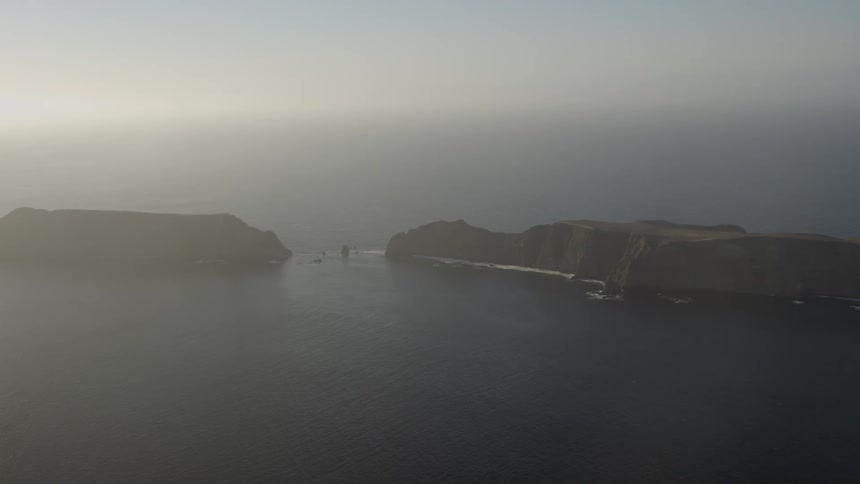 A waterway with two large masses on the side and it is foggy