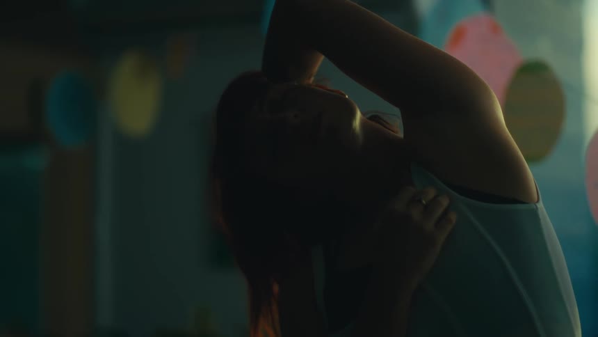 Woman in an indoor space dancing with one hand on her head