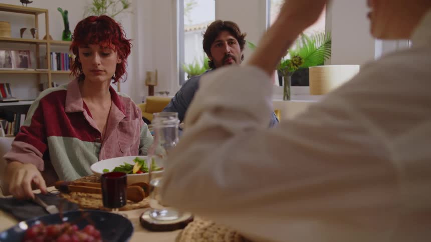 Man and two women sitting at a served table talking