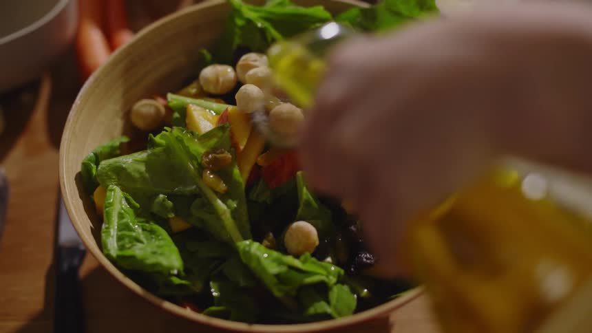 A person puts oil on the salad