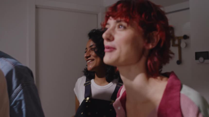 A group of joyful friends embraces exchanging hugs and kisses as they greet one another in a room