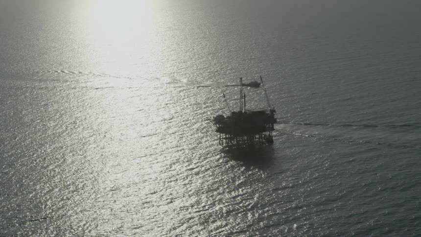 Aerial view of an oil rig in the ocean at sunset