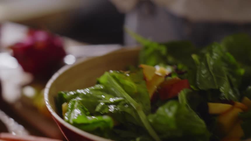 Woman pouring pieces of fruit into a jar with salads