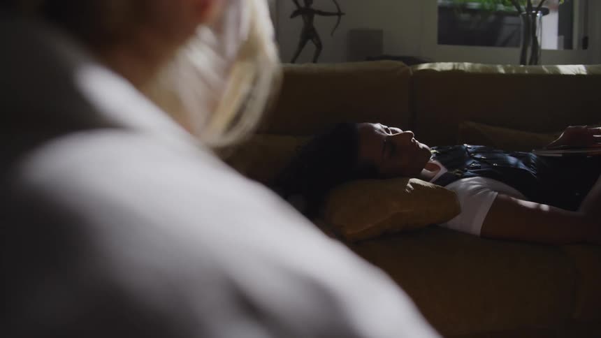 A woman is talking to another woman on the couch