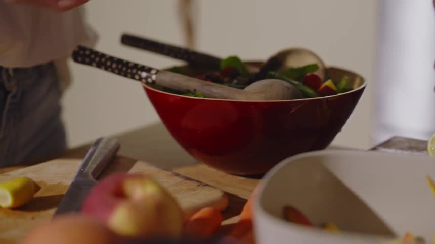 Hands of two women seasoning a salad