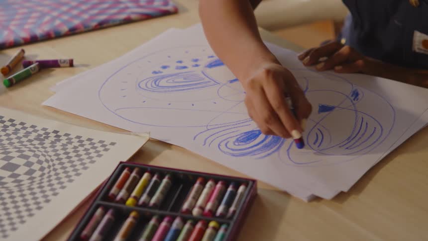 Womans hand with blue crayon drawing