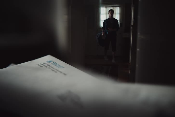 Man entering the house and in a hallway picking up a letter