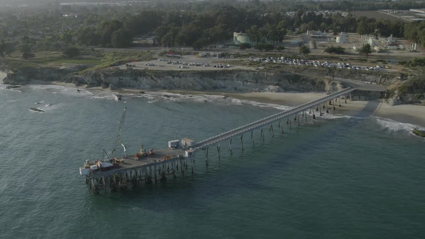 An industrial crane is sitting on pier that juts out into the ocean