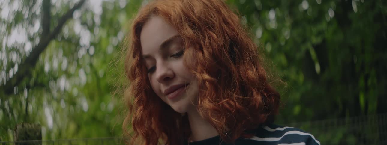 Portrait of a redheaded woman looking down with a slight smile