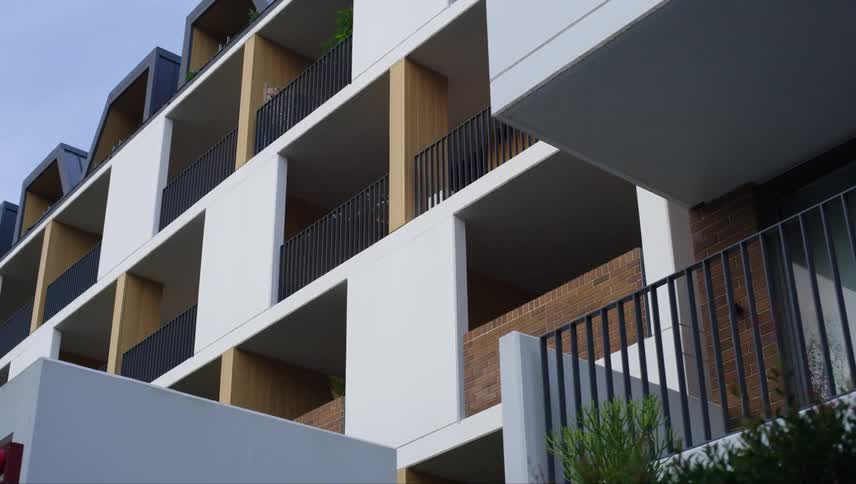 A modern apartment building with a clean minimalist design of white and gray walls with wooden accents on the balconies