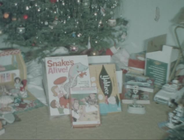 A pile of wrapped christmas presents sits below a decorated christmas tree