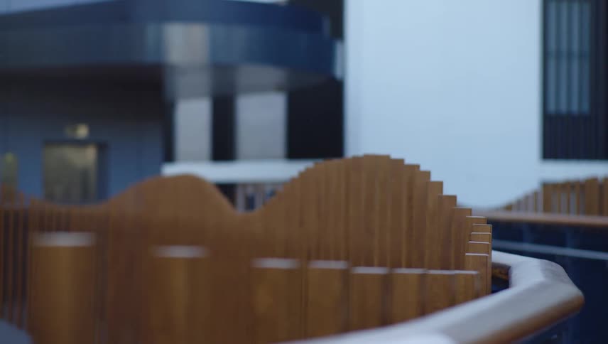 The interior of a large commercial building has a curved wooden fence