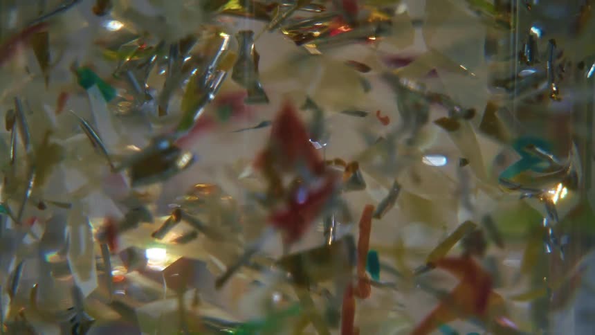 Extreme close up of an object with a dense liquid and colorful sequins in abstract motion