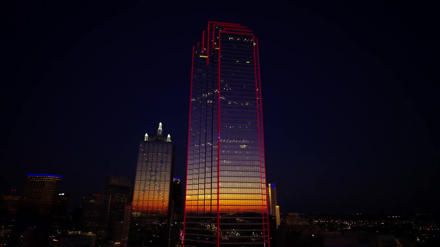Skind skyscraper enlightened at night with red lights outlining its structure