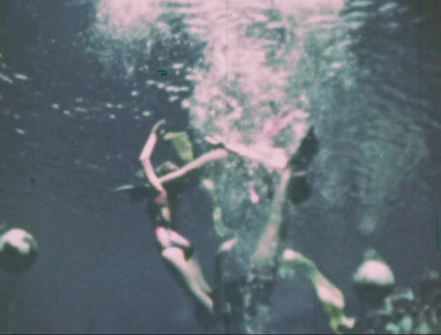 A trio of synchronized figures do triangular figures inside a pool
