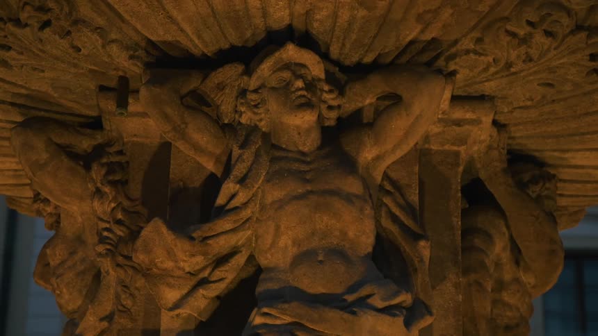 Classical statue illuminated and with water reflection