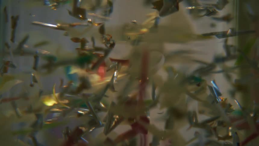 Silver confetti falling into an abstract liquid