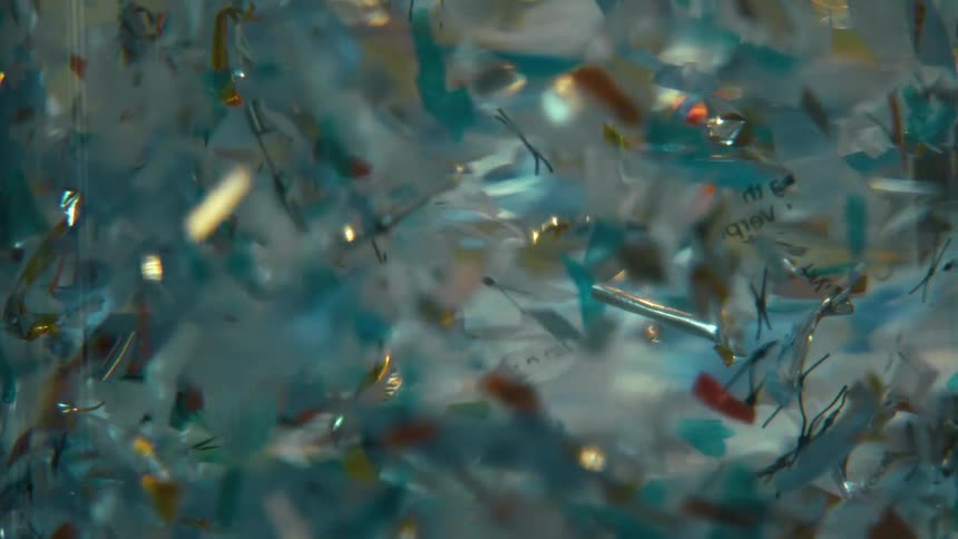 Close up of shiny particles floating on a clear liquid reflecting light
