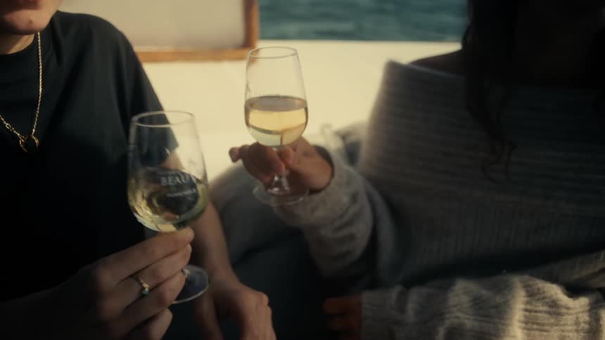 Two women on a boat drinking white wine in tall glasses