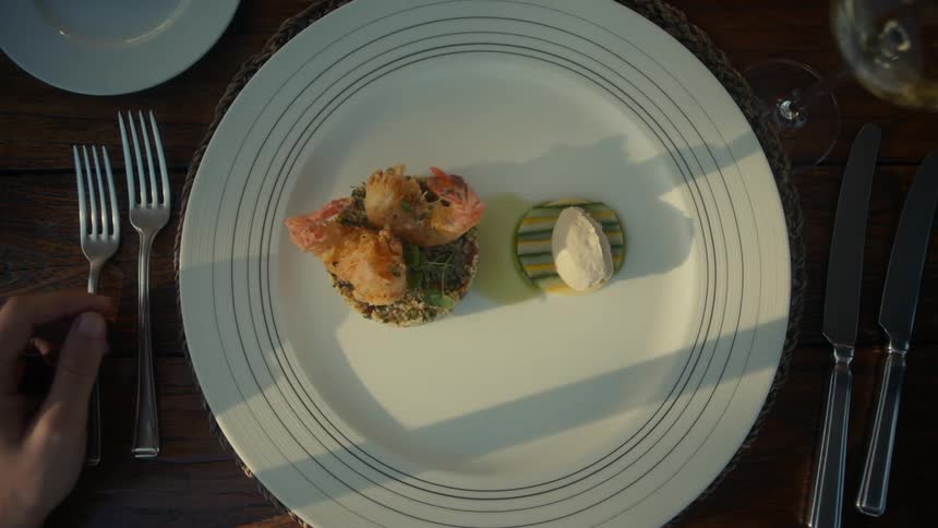 Plate of seafood being placed on a table with cutlery